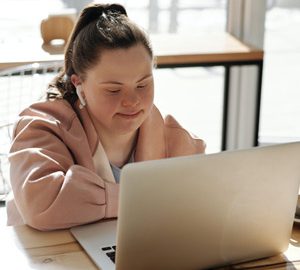 Femme atteinte du syndrome de Down assise devant son ordinateur